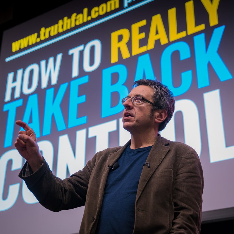 Man giving lecture in front of screen with words.