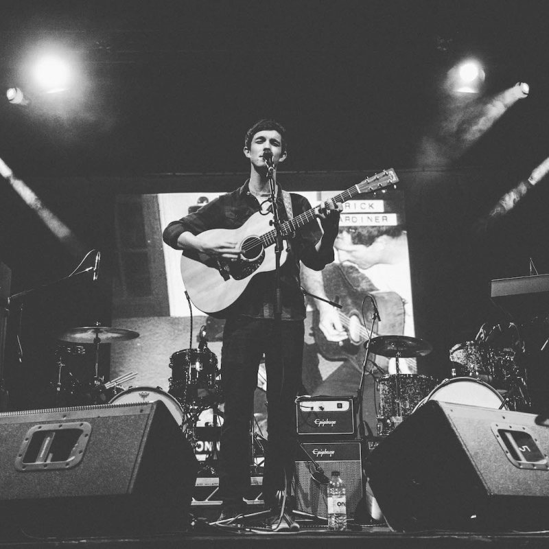 Falmouth University music student on stage playing guitar.