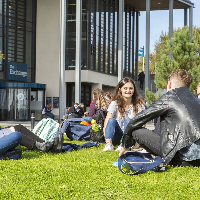 Students sitting on grass at Penryn campus.