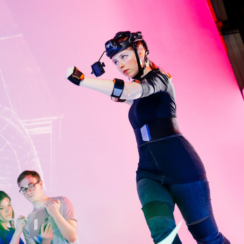 Female student wearing games development headset in front of a pink background