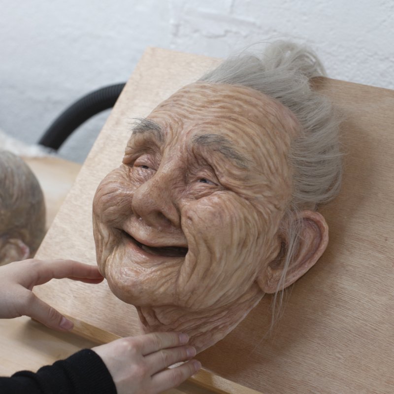 A sculpted head of an old woman with grey hair