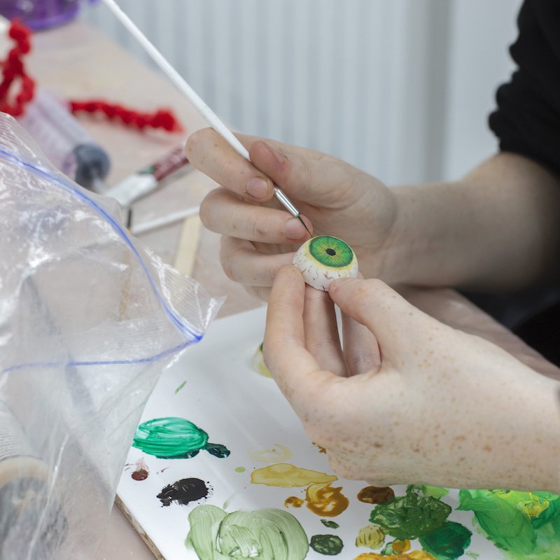 A student painting a 3D eye with green paint
