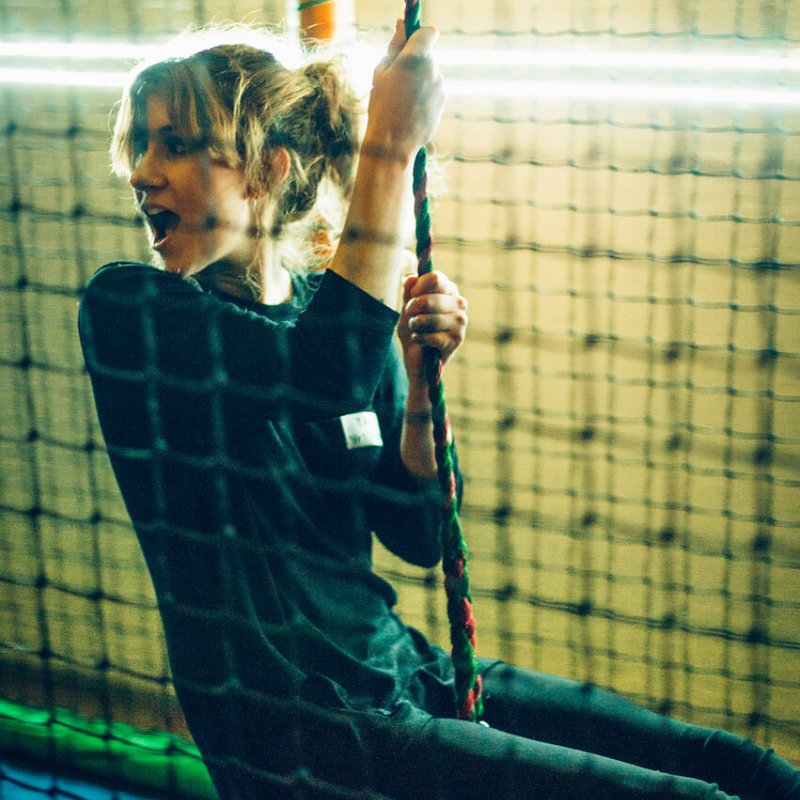 Falmouth University student swinging on rope at activity centre.