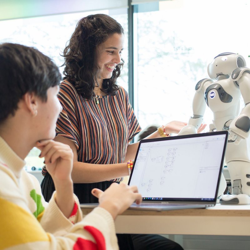 Two Robotics students operating a small robot with a laptop