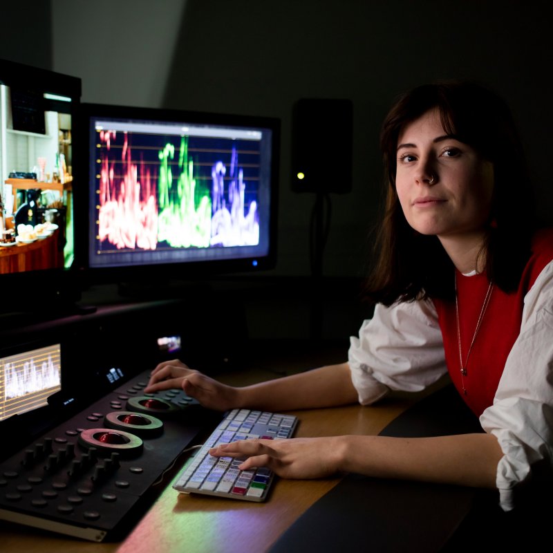 Student at editing desk with several screens in front of her.