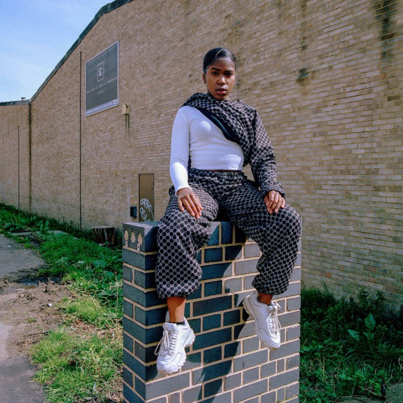Girl sitting on a brick wall in front of building