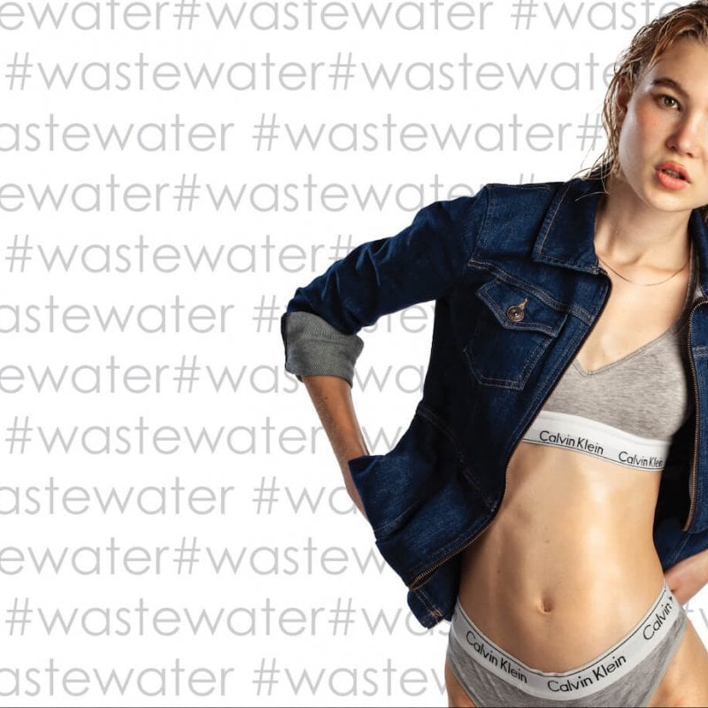 A woman in Calvin Klein grey underwear and a denim jacket with #wastewater text in the background
