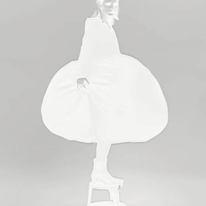 Negative image of a woman wearing a dress, standing on a stool