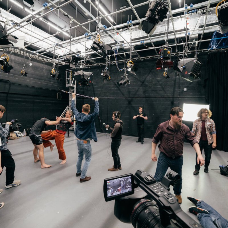 Film students combat fighting and filming in a studio.