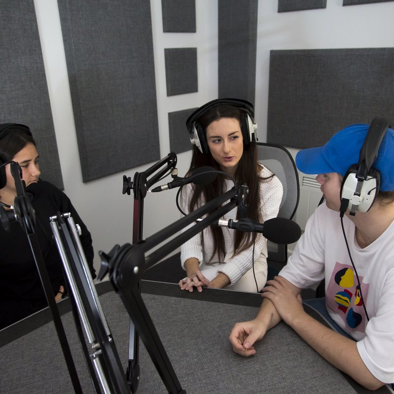 Students with headphones and microphones in grey recording room.