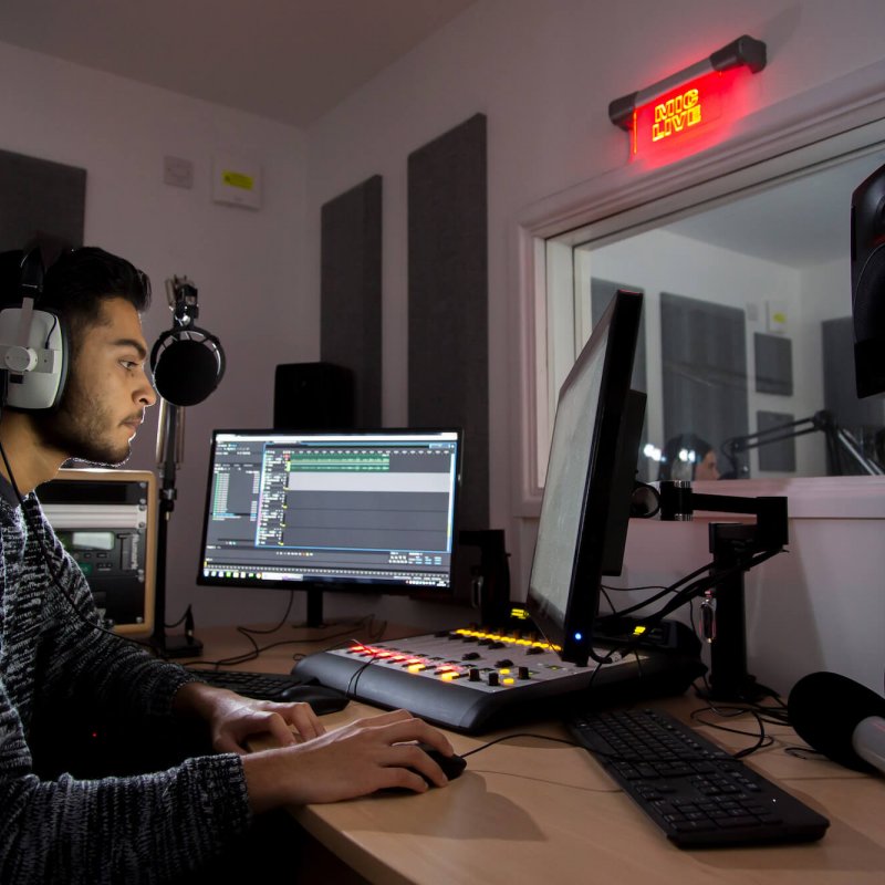 Student wearing headphone while sat in a mixing studio