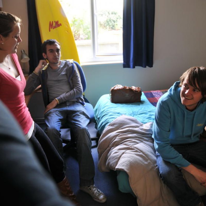 Students sitting around a bedroom and chatting.