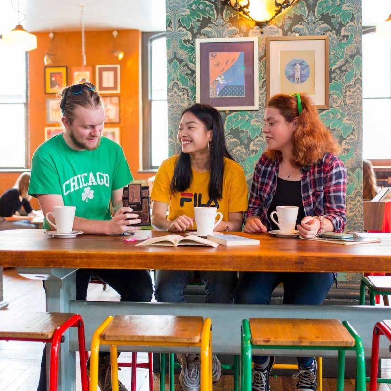 Brightly dressed Falmouth students having coffee in brightly decorated cafe.