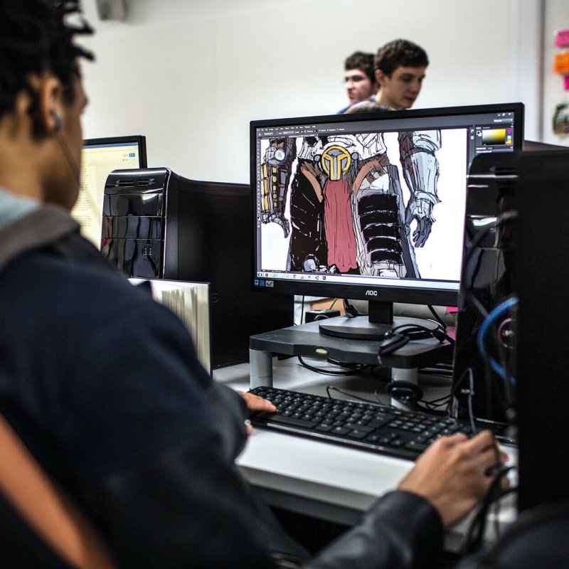 A male student working at a computer with a game animation