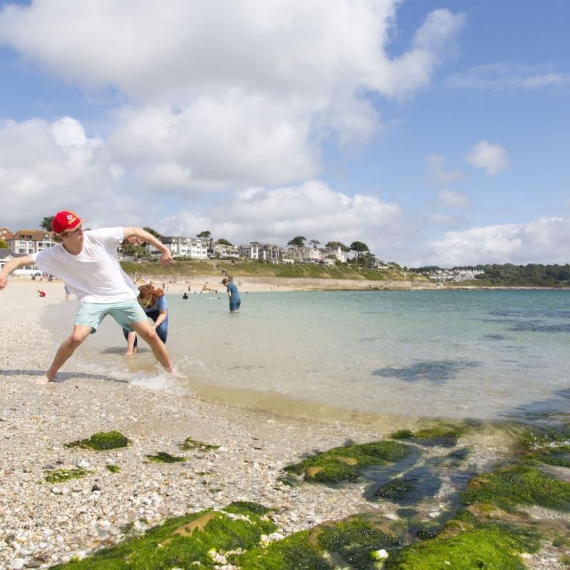 Falmouth University students throwing stones on the shore