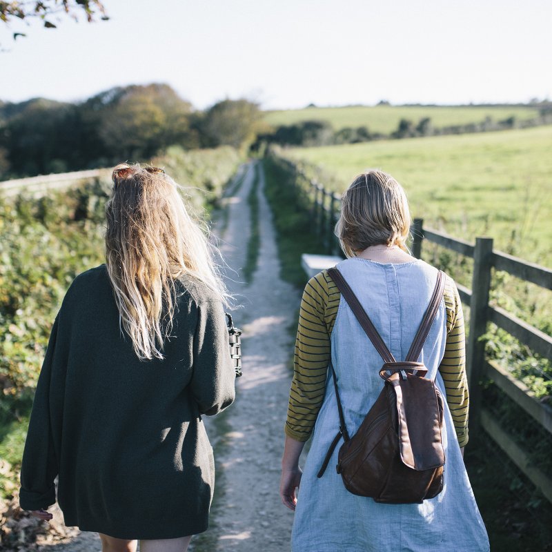 Backs of two students walking up a path in a field.
