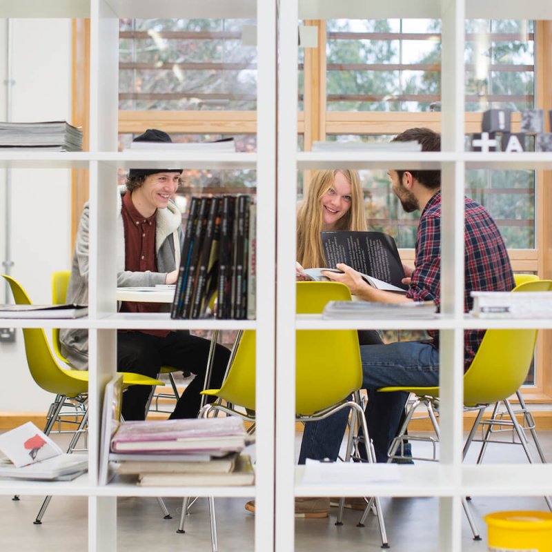 Falmouth University students viewing through a square shelving unit