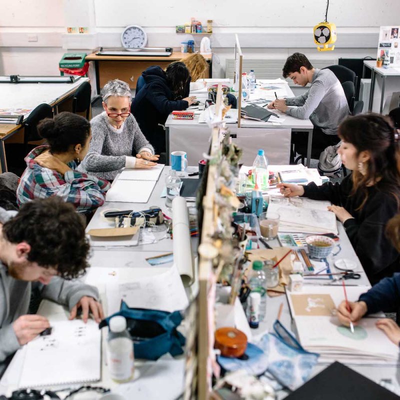 Illustration students in busy studio at desks drawing.