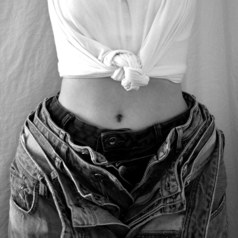 White t-shirt tied in a knot with a bare midriff and open jeans