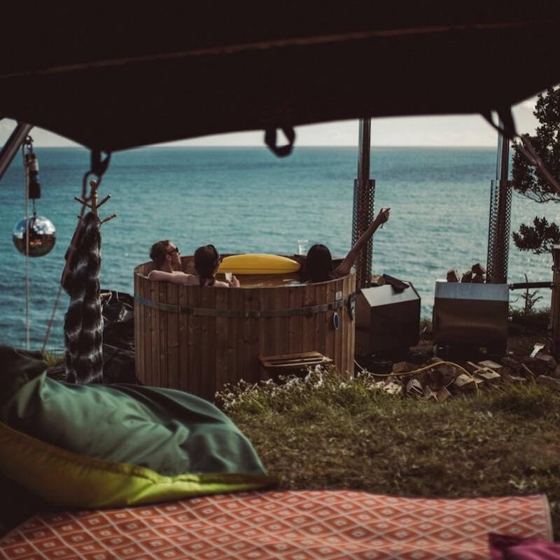 Group relaxing in a wooden hot tub with incredible sea view.