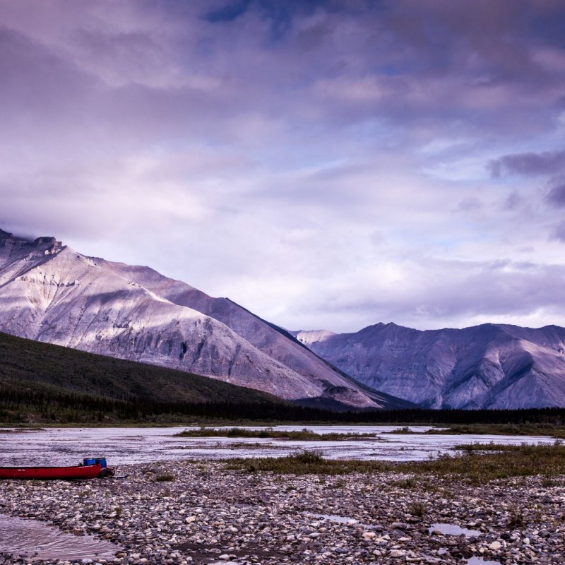 A landscape image: a canoe is pictured with mountains in the background 