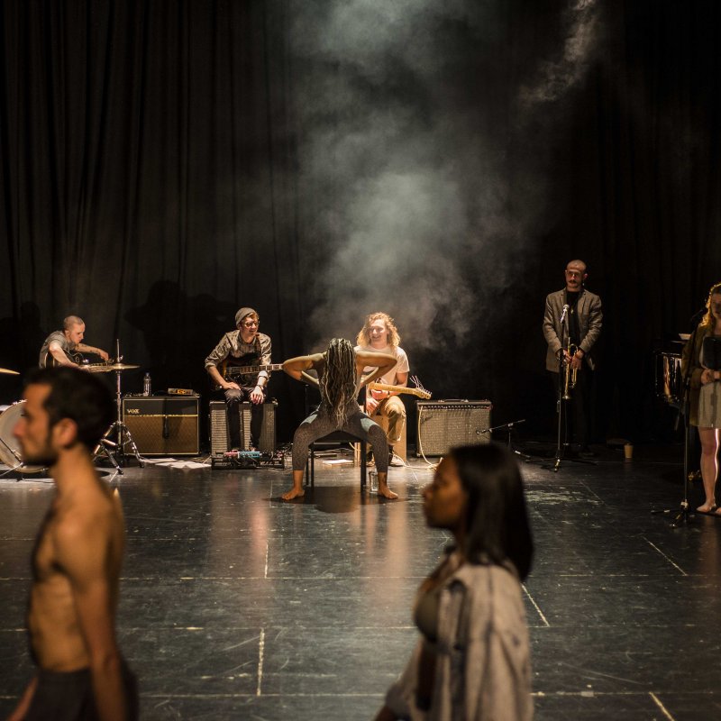 Students on stage with guitars, microphones and dancing.