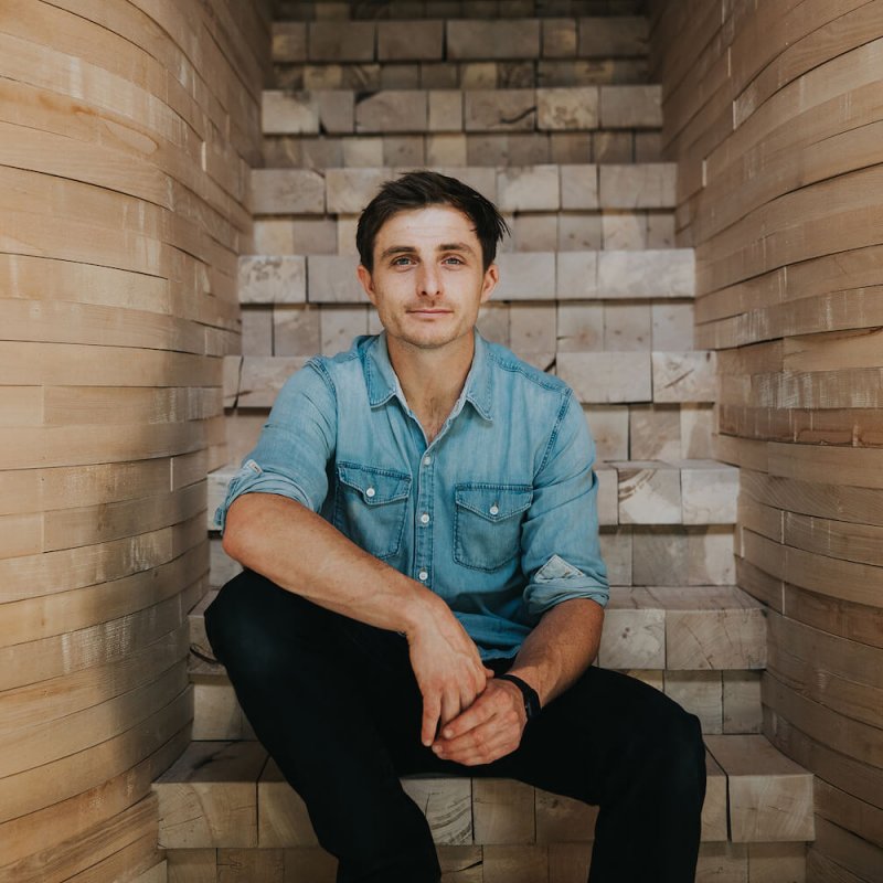 Falmouth University alumni Tom Raffield sitting on wooden steps