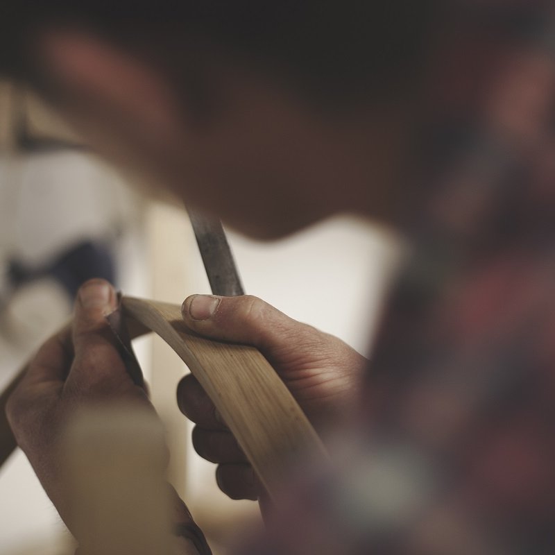 A person bending a strip of wood with their hands