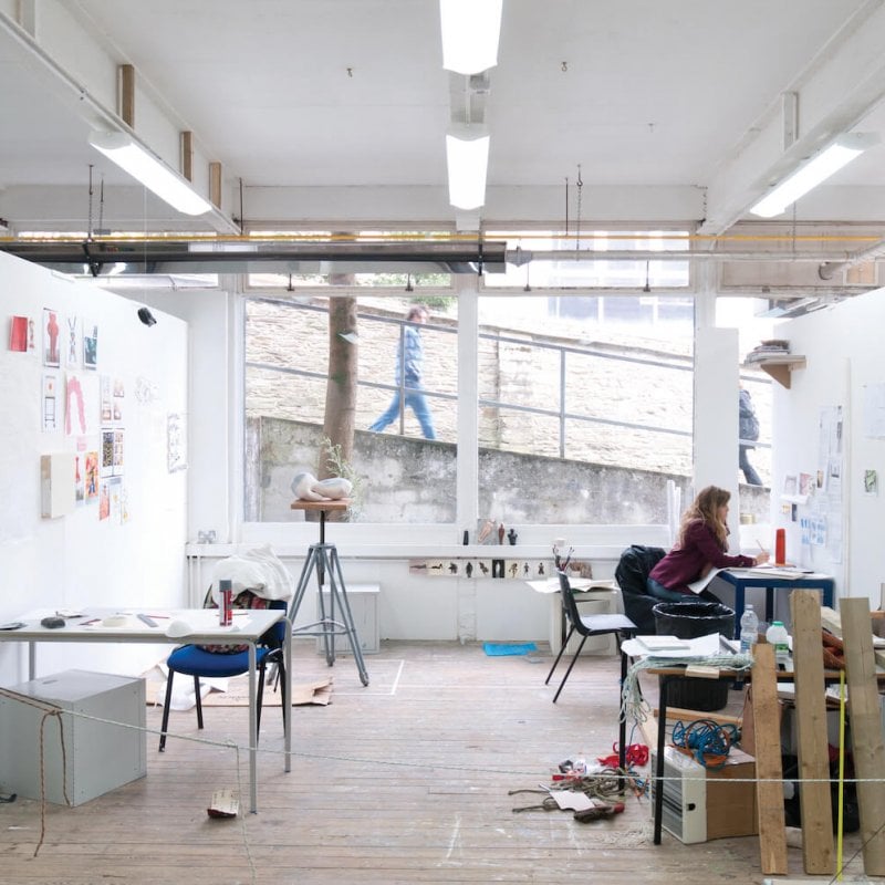 Art student working in studio with large window on Falmouth campus and person walking past and looking in.