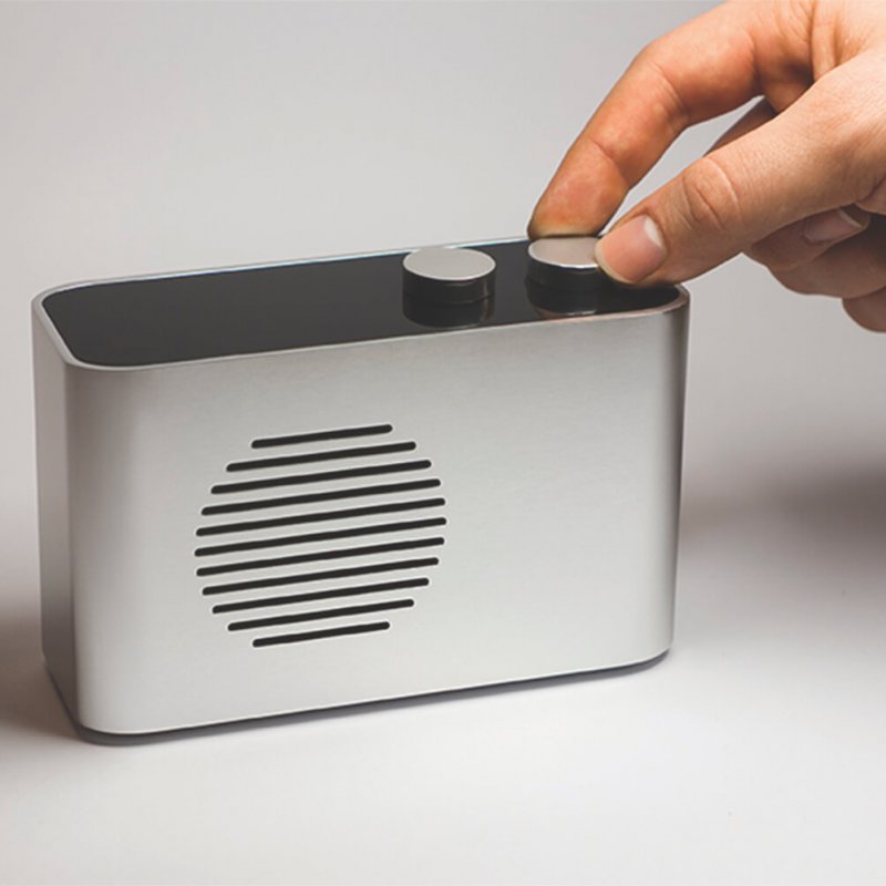 A hand tuning a silver radio