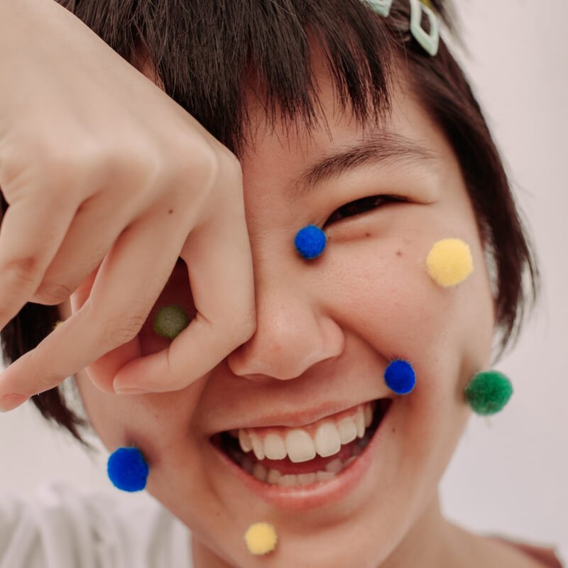 Smiling Asian girl with pompoms on her face