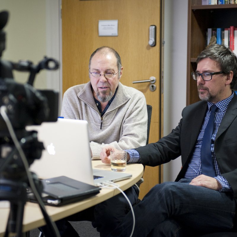 Tutors sat at desk in front of laptops with camera pointing towards them.