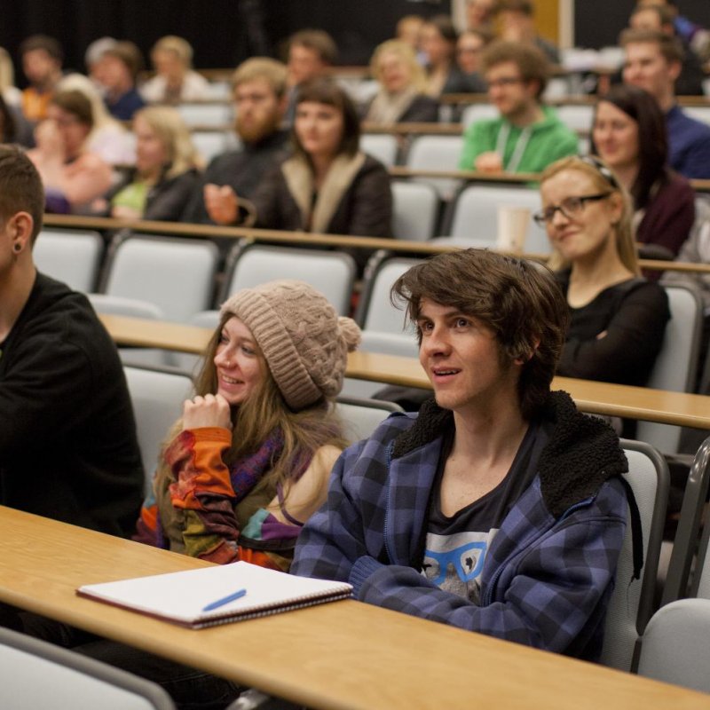 Students listening and smiling in lecture theatre.