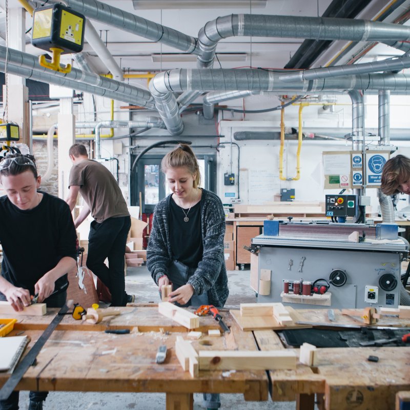 Female student and two male students in wood workshop