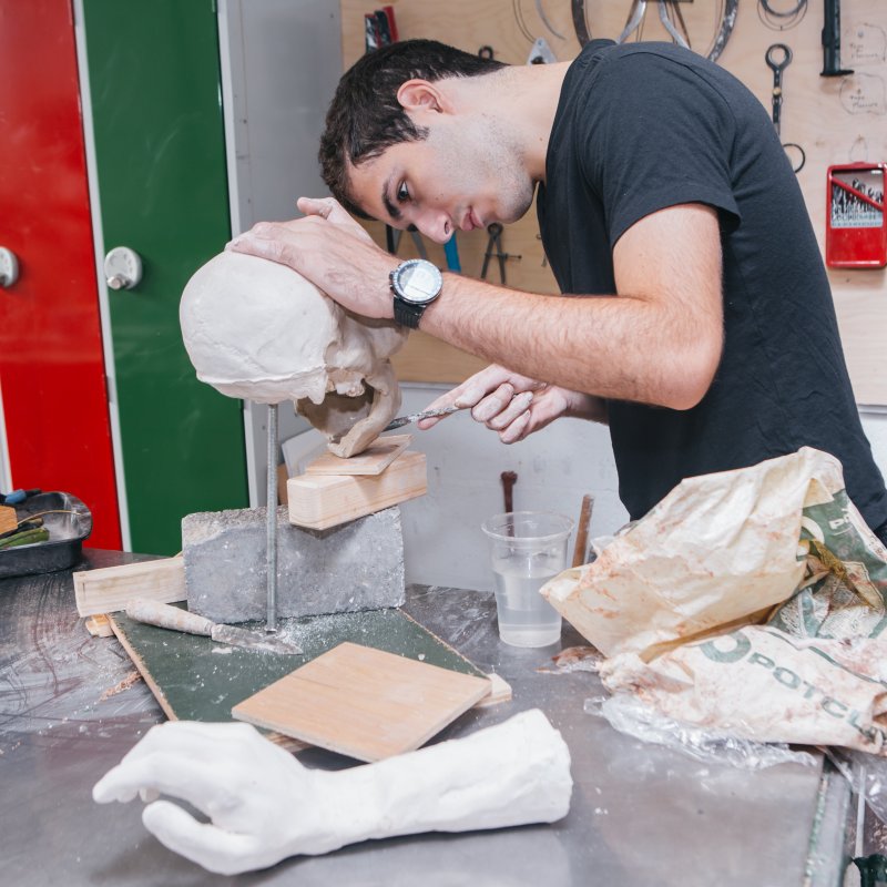 Male student working on a ceramic skull in workshop