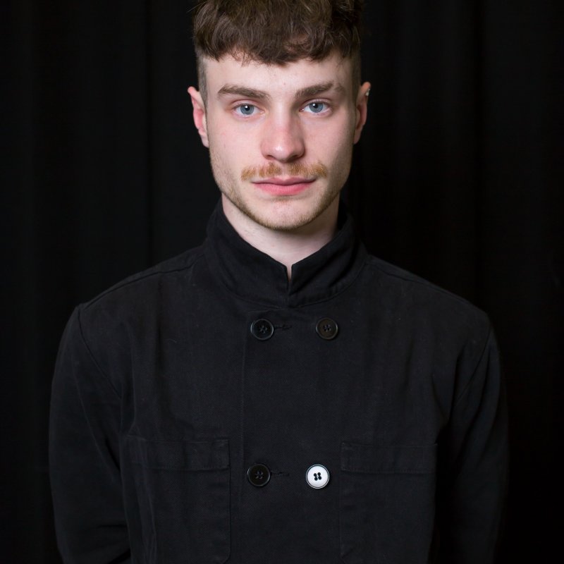 Student portrait - a white man with short hair poses in black clothing