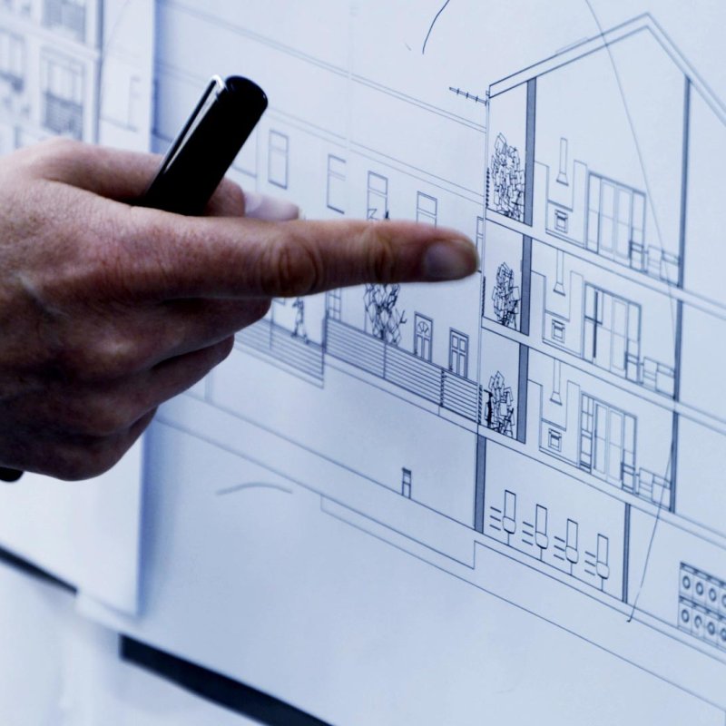 A hand pointing at an architectural drawing of a building