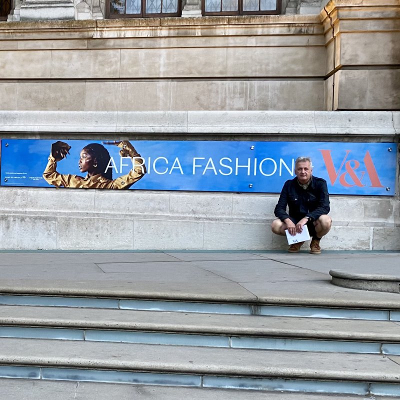 A man crouches in front of the Victoria & Albert Museum in London