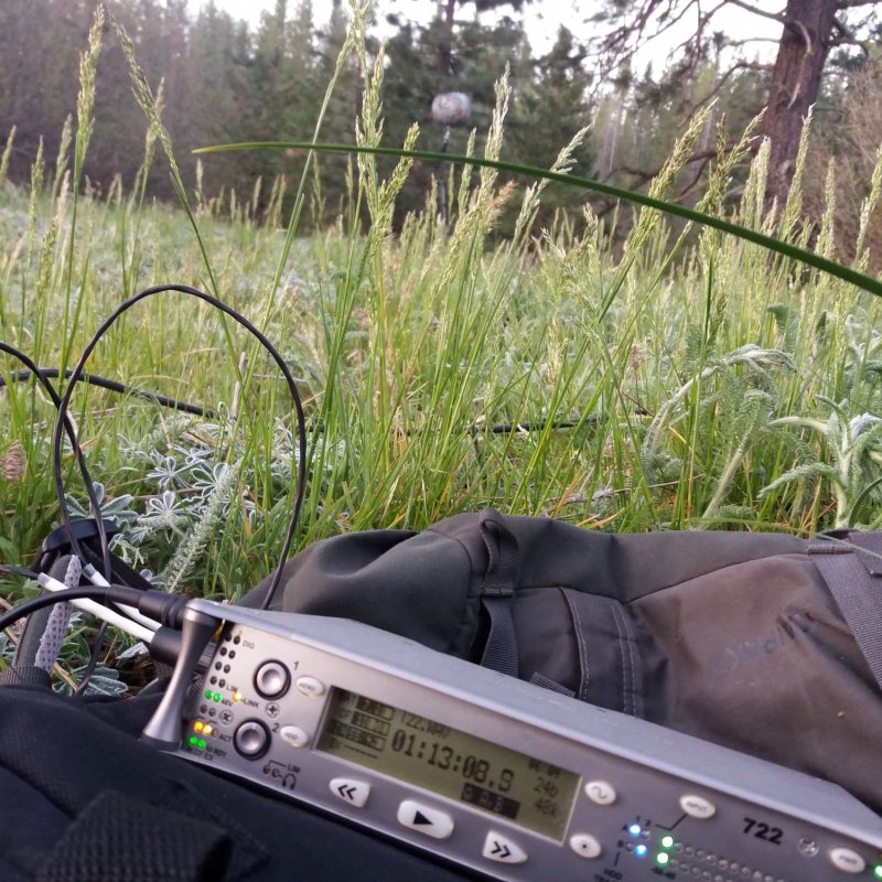 Close up of recording equipment laying in the grass with fields in the background