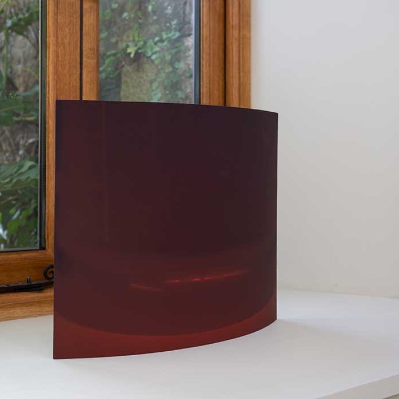 A brown square sculpture resting on a window sill 