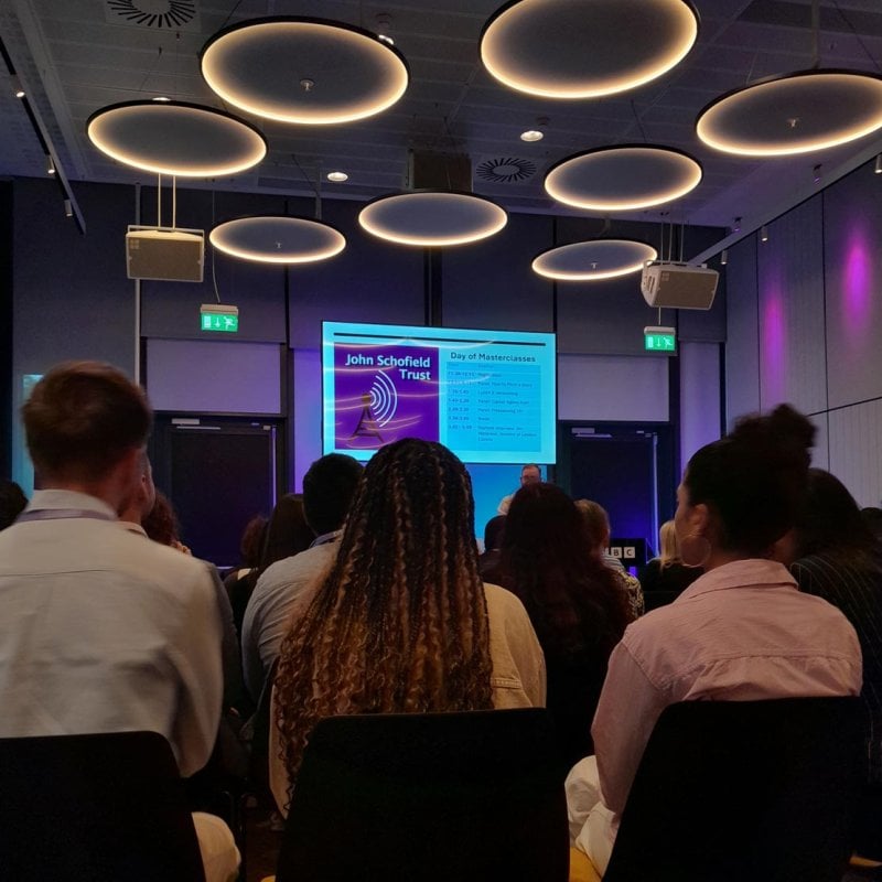 A row of people sat on chairs looking at a projection on the screen