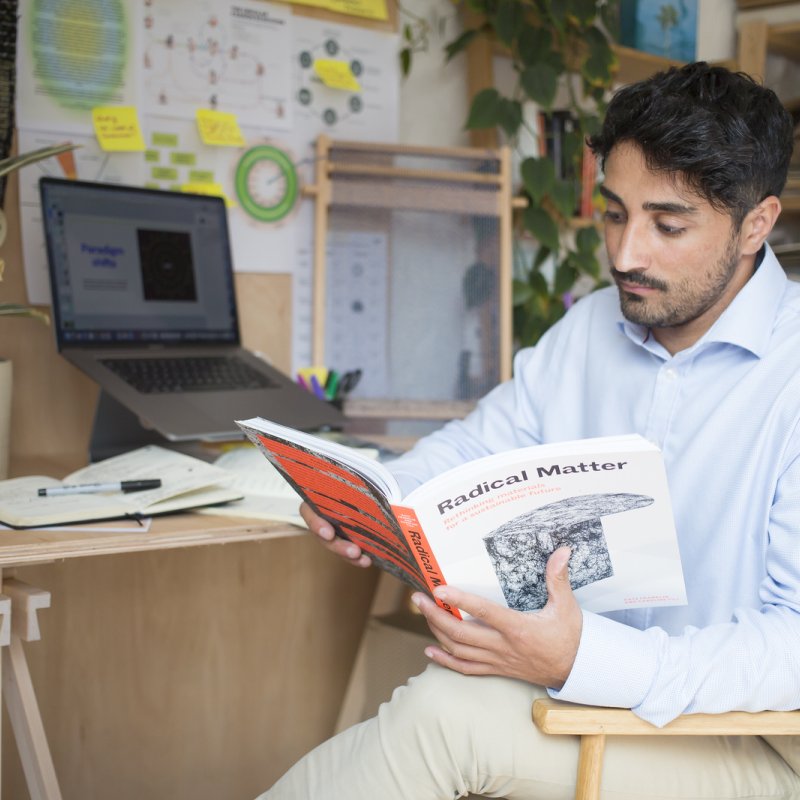 A man sat at a desk looking at a book
