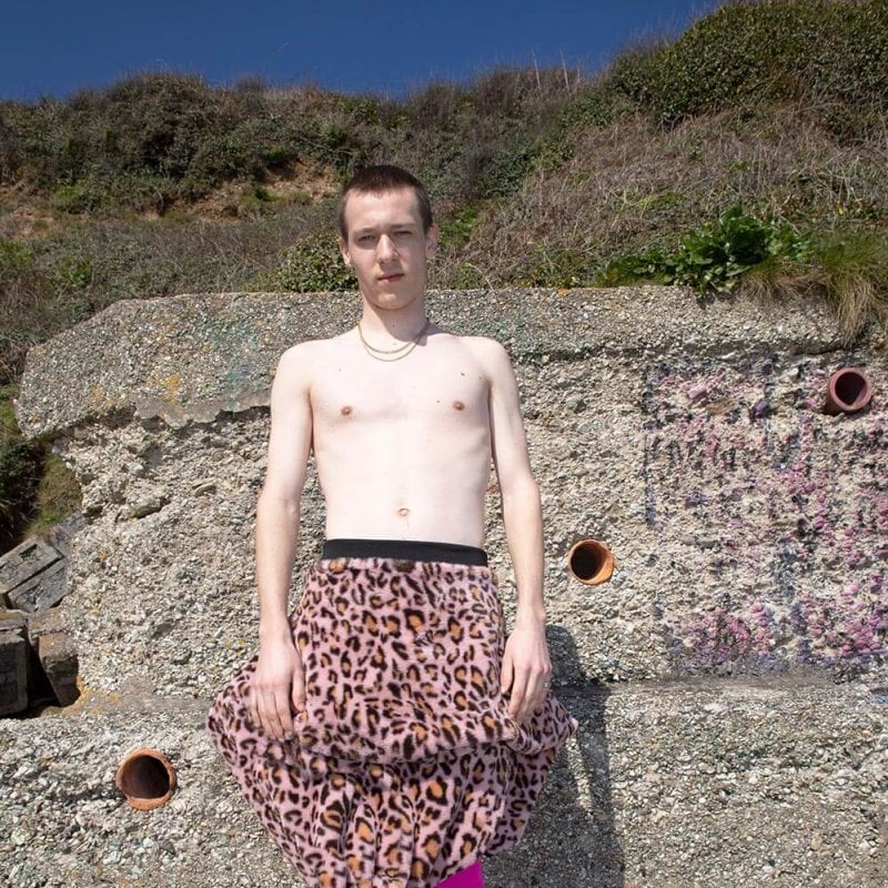A topless man wearing pink tights and pink leopard print skirt