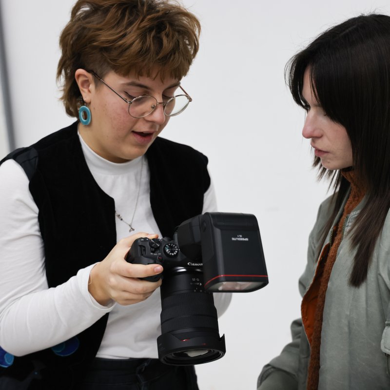 Two people looking at a camera, the person on the left is holding it