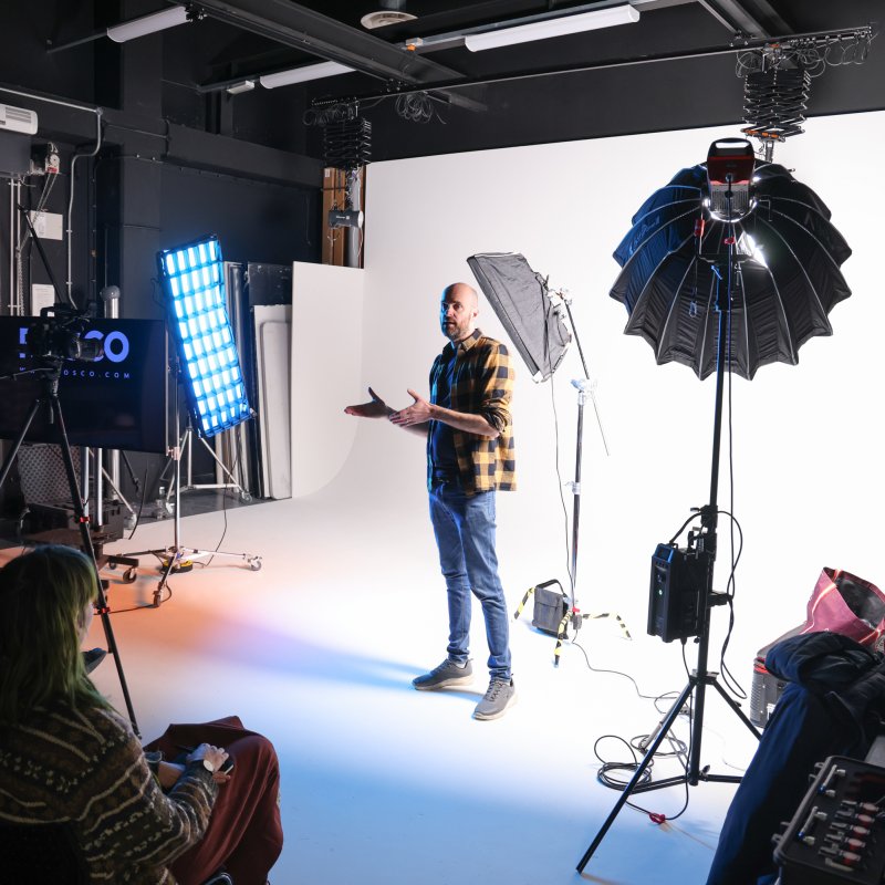 A person in a yellow check shirt standing in front of a white screen