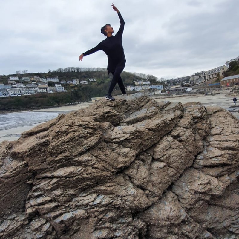 Julie Felix standing on beach rock in ballet pose