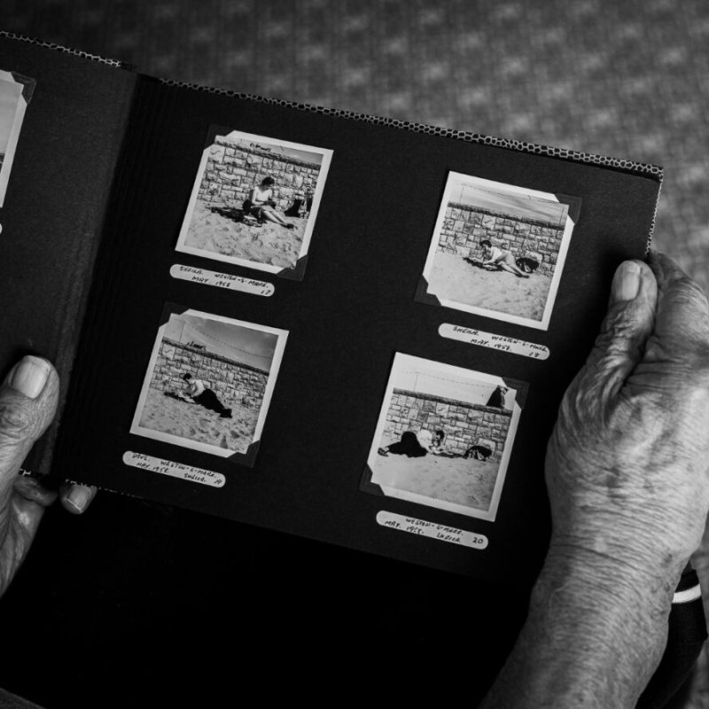 An over-the-shoulder photo of a photo album being held by an elderly person 