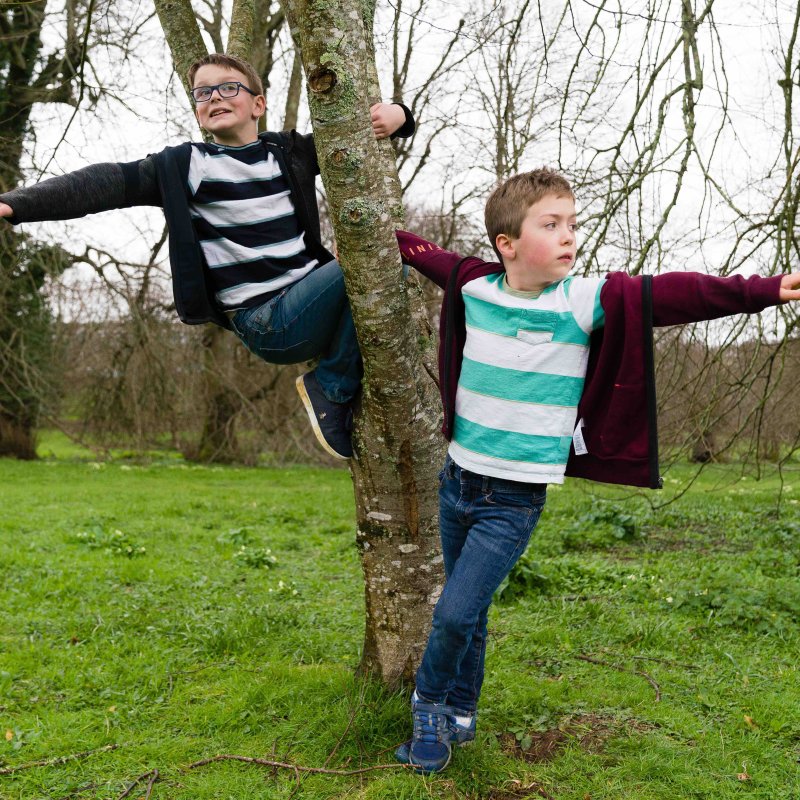 Two children dancing around a tree