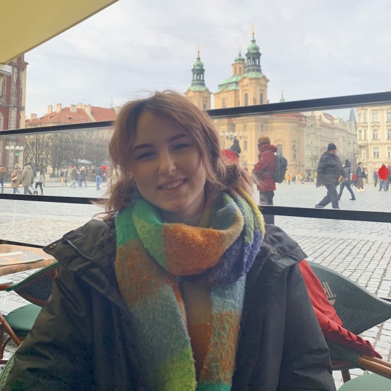 A young woman with red hair wearing a colourful scarf and coat