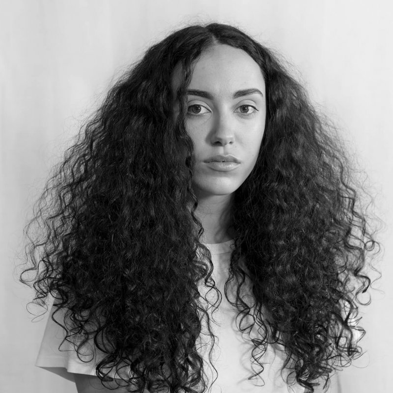 Black and white photographic portrait of a woman with long curly hair